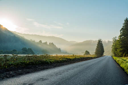 road near the mountains and forests ray of sun on the trees. beautiful background.の写真素材