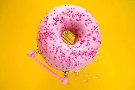 sweet pink donut in a shopping cart on a yellow background.の写真素材