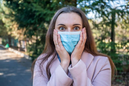 beautiful girl with a medical mask on the streets. emotion is frightened.