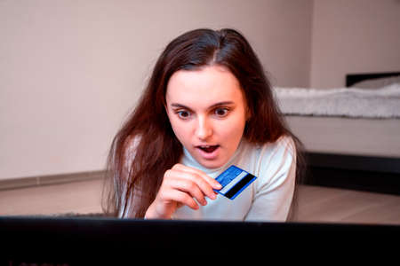 girl surprised by discounts in an online store holding a bank card. online shopping.の写真素材