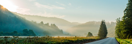 panorama of mountains in the fog near the road at sunrise. beautiful backgroundの写真素材