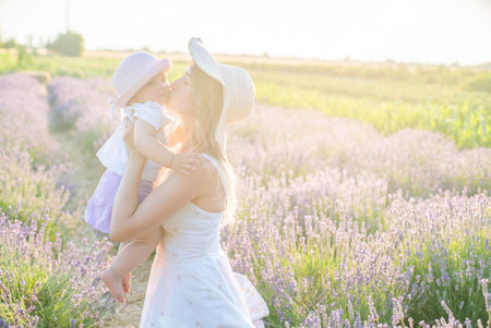 mom with daughter on a lavender field at sunrise. Harmony with nature. Happy childhood.の写真素材