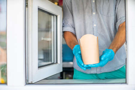 the seller through the window serves food in the package.の写真素材