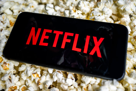 Uzhhorod, Ukraine. October 19, 2021 A man watches movies on Netflix. Internet service. on smartphone black image netflix phone lies on popcorn.のeditorial素材