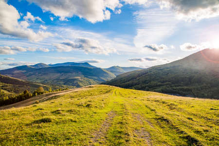 hilltop on the background of a mountain range with blue sky and sun rays on a teali summer day. Mountain landscape.の写真素材