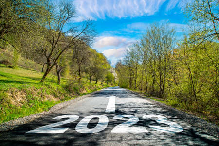 road 2023. Spring landscape near the road in the woods .on the asphalt road written 2023 in front. blue sky with clouds.の写真素材