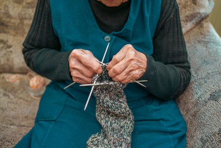 Grandmother knits socks by hand. Digital camera filming commercial video blog or vlog of man teacher vlogger coach recording business device shooting videoblog vlogging conceptの写真素材