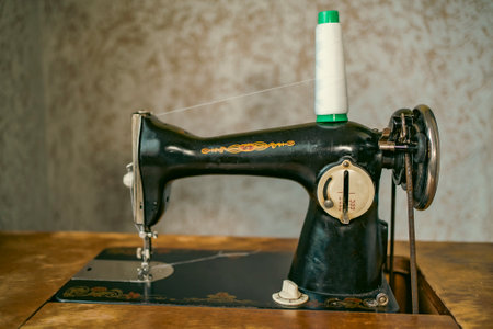 Senior woman in spectacles use sewing machine. wrinkled hands of the old seamstress.elderly woman . Old sewing machine Classic retro style manual sewing machine ready for sewing work.の写真素材
