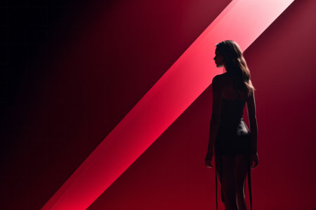 Silhouette of a woman standing against a red geometric background, creating a dramatic and mysterious atmosphere.の素材