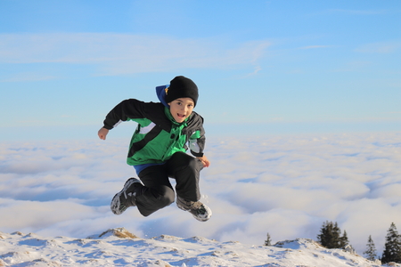Child jumping in the air over the cloudsの写真素材
