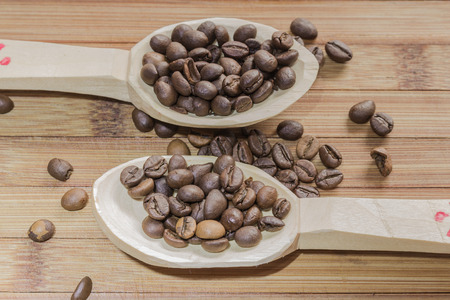 Coffee beans and two wooden spoon on wooden backgroundの写真素材