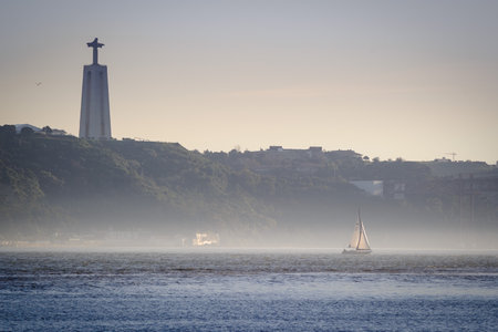 Sailing Boat on the Tagus River with Cristo Rei Statue. Lisbon Portugal.