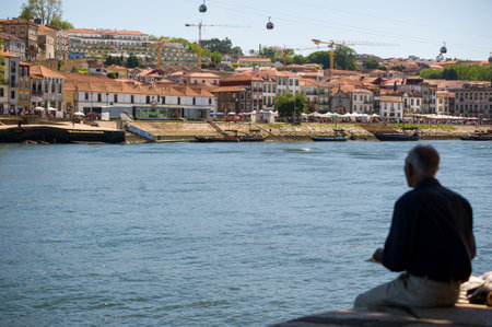 Man by Douro River in Porto, Portugal, with Cityscapeの写真素材