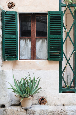 Rustic Building with Wooden Shutters and Aloe Plantの写真素材
