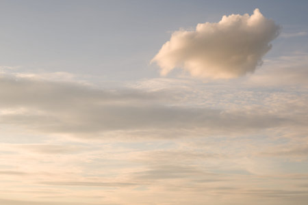 Beautiful evening sky with one distinct fluffy cloud illuminated by soft sunset light for nature and tranquil backgroundの写真素材