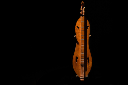 Dulcimer, dramatically lit on black background, on stand.の写真素材