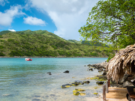 Red boat waits off a tropical beach. Tranquil summer scene in the Caribbean Islandsの写真素材