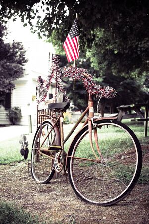 American flag and red white and blue garland adorn an old bicycleの写真素材