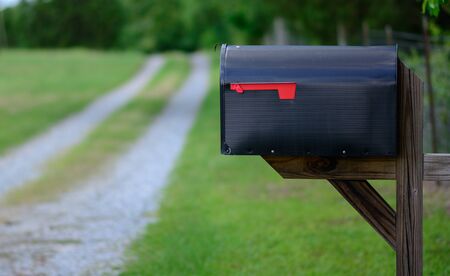 A large mailbox with the flag down along a gravel road.の写真素材