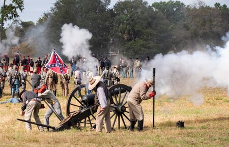 Brooksville, FL - January 19, 2020: Civil War reenactors fire a large canon, with a confederate flag in the background, at an event in Brooksville, FL.のeditorial素材