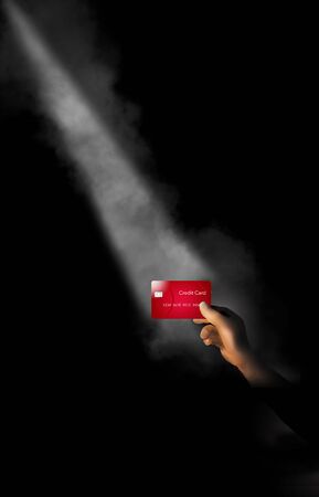 A hand holds a credit card in a shaft of light with a little fog. The theme is focusing on credit cards or one card in particular.の写真素材