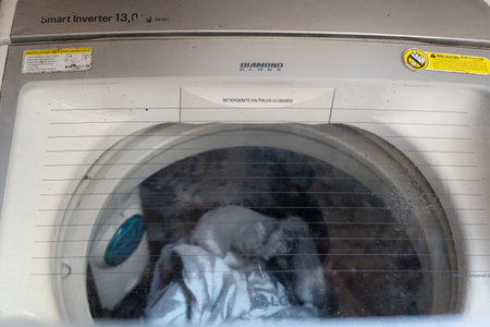 LG washing top view turned on and opened door, with clothes inside and detergentの写真素材