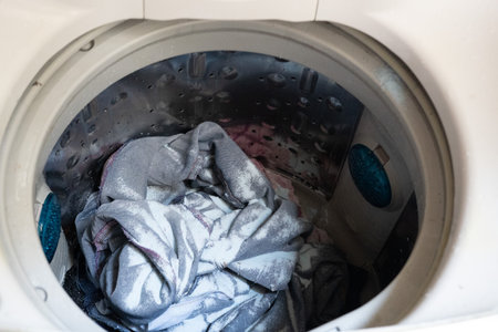 LG washing top view turned on and opened door, with clothes inside and detergentの写真素材