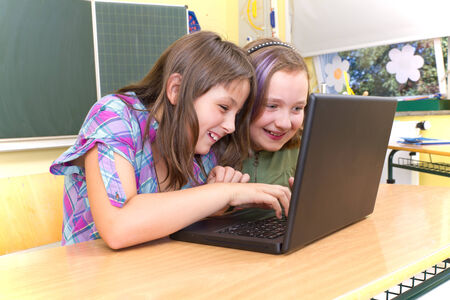 Girls in a classroom playing with computer
