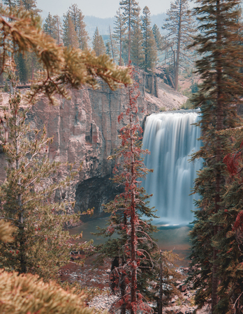 Long exposure of Rainbow Falls waterfall in Mammoth Lakes, California, USA near Devil's Postpile.  High Cliffs, surrounding trees, and blue sky. Rainbow falls is the highest waterfall of the San Joaquin River.  101 feet tall it often creastes a rainbow from the mist on a sunny day.の写真素材