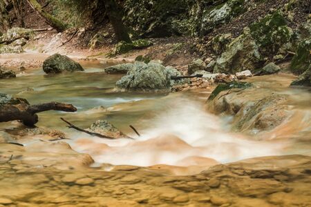 Rapid river running through the stones in an amazing green mediterranean mountain forest with broken...