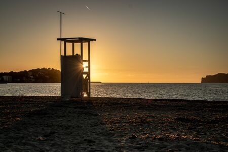 Sunset on the sandy beach in a romantic mood with a life guard towerの写真素材