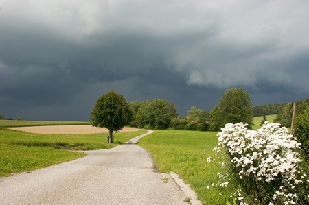 landscape with a little road before a thunder strom with dark skyの写真素材