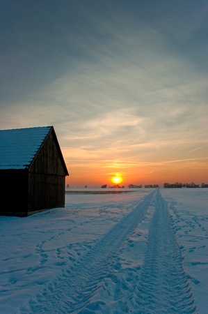 a wooden hut in a winter landscape during sunsetの写真素材