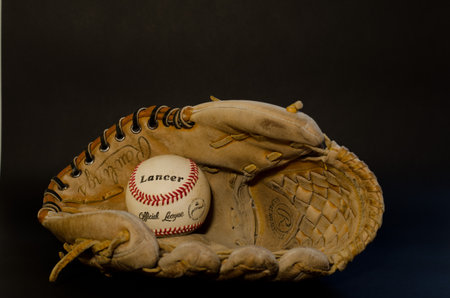 glove leather with baseball stitching and inside a white baseball ball: behind a black backgroundのeditorial素材