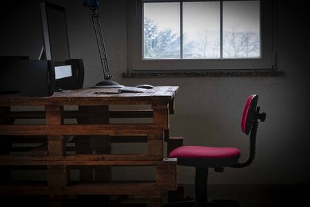 wooden pc station with white keyboard and mouse monitor next to a window light