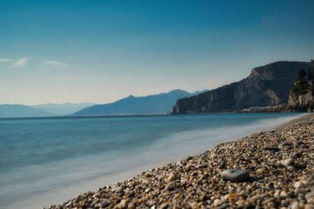 Beach with pebbles and mountains in the background. Beautiful seascape.の写真素材