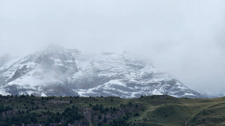 Mountain landscape with snow-capped peaks in the clouds.