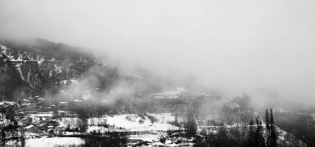 Panoramic view of the mountains covered with snow and fog.の写真素材