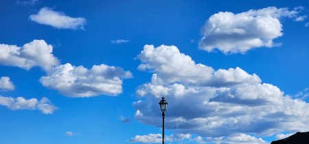 a street lamp with electric light and in the background a sky of clouds on a summer day in the...