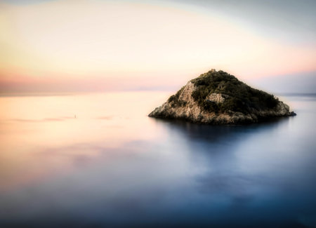 the island of Bergeggi, on the Ligurian coast, is reflected in the waters of the Mediterranean Sea on a splendid summer day at the end of Julyの写真素材