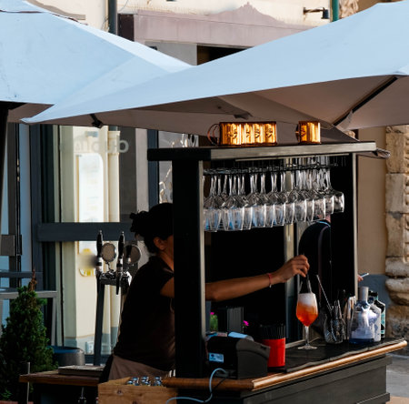 bartender prepares a cocktail, a spritz in a bar on the cathedral square of Cefalù, in the province of Palermo in Sicily, during the summer of 2024の写真素材