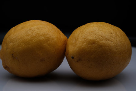 pair of yellow lemons on black background in close-up to be eaten
