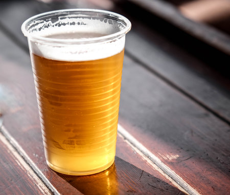 Plastic cup of ice cold beer with blurred background