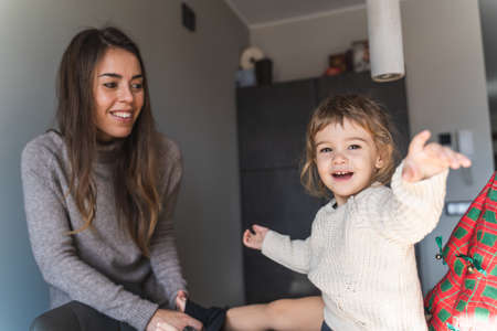 Young woman laughing with her daughter in the living room