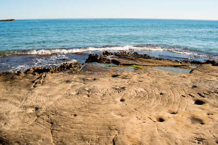 Sculpted rock surface with a spiral by the seaの写真素材