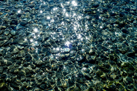 Sunlight through the pebbles on the shore of the sea