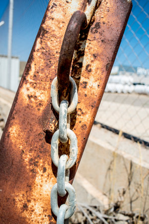 Rusty chain on a rusty metal chain link fence on a sunny day