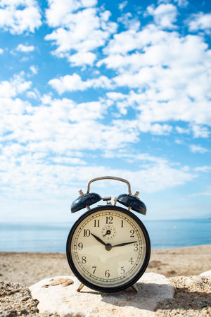 Retro alarm clock on the beach with sea and sky background.の写真素材