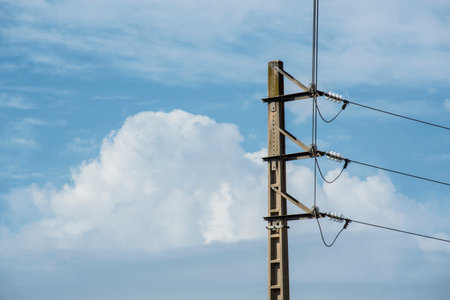 High voltage post with blue sky and white cloud background, electricity post