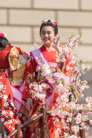 Washington, D.C., USA - April 14, 2018 Japanese woman wearing a kimono standing behind cherry flowers in the 2018 National Cherry Blossom Paradeのeditorial素材